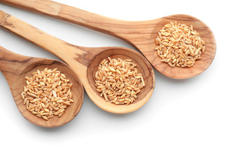 Spoons with wheat grains on white background