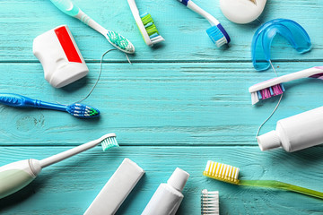 Frame made of toothbrushes, paste and dental floss on wooden background