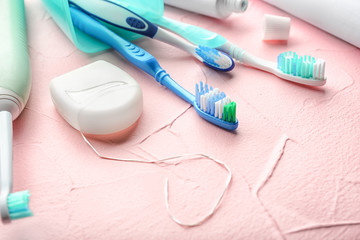 Toothbrushes and dental floss on color background