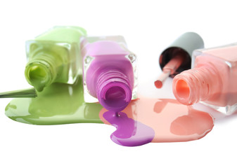 Open bottles with spilled nail polishes and brushes on white background