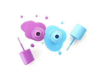 Open bottles of nail polishes with brushes on white background