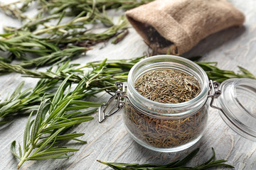 Glass jar with dried rosemary on table