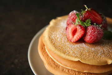 Plate with delicious pancakes and strawberries on dark table, closeup