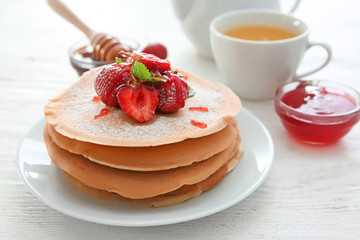 Plate with delicious pancakes and strawberries on wooden table
