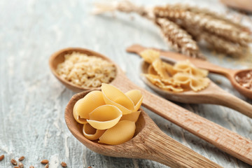 Fototapeta na wymiar Spoon with wheat pasta on wooden table