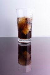Cola and ice cubes in glass on white background with selective focus and crop fragment