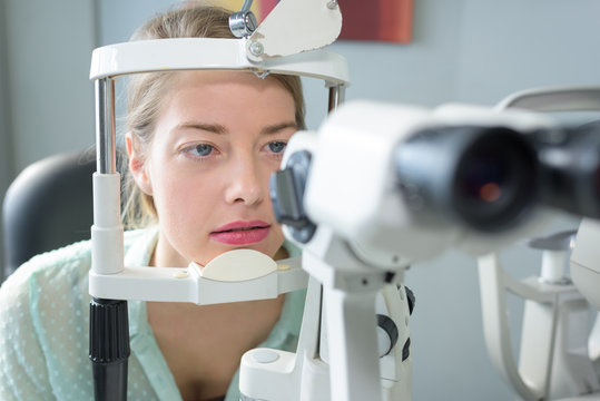 portrait of woman with head in opticians examination equipment