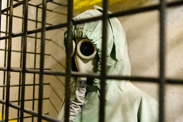 man in gas mask in chemical protection behind bars