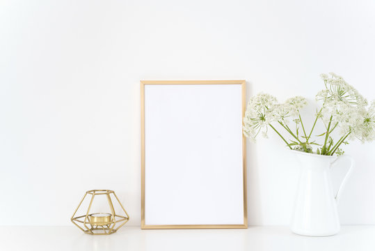 Gold frame mock up with a Aegopodium in jug and candle. Mockup for headline design.Template for lifestyle bloggers,media