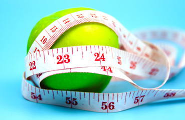 Close up of green apple and measuring tape isolated on blue pastel background