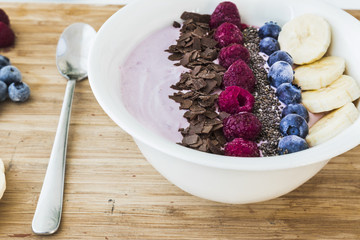 Smoothie bowl with fresh berries, banana, chia seeds and chocolate for healthy vegan and vegetarian diet breakfast