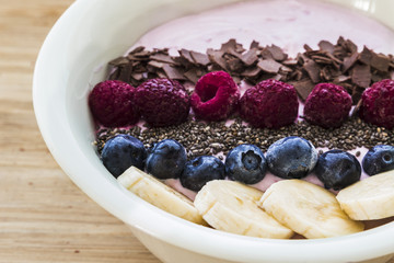 Smoothie bowl with fresh berries, banana, chia seeds and chocolate for healthy vegan and vegetarian diet breakfast