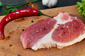 Fresh beef steak, wooden spoon, Assortment of Fresh Vegetables, aromatic herbs, spices and vegetables for cooking , on black  background, top view. Meat