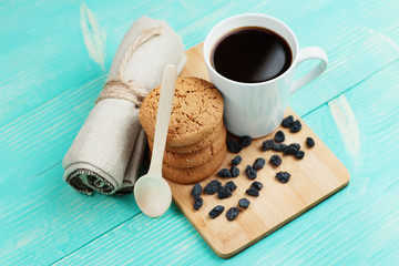 Cup of tasty coffee with raisins and biscuits over vintage wooden table.