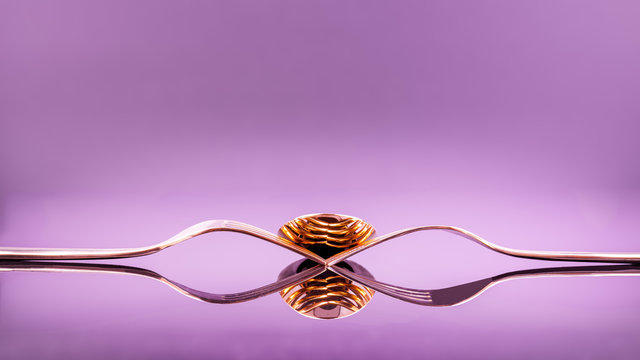 golden forks and spoon decoration arrangment on reflection ultra violet surface and background