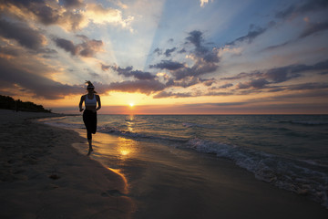 Naklejka premium Woman running on the beach during a beautiful sunset.
