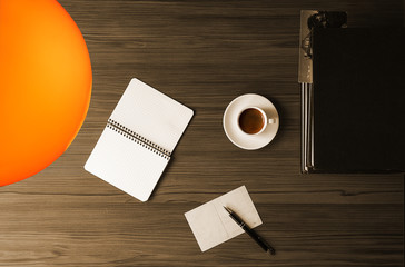 blank postcard, pen, books and coffee on the desk, illuminated by a table lamp