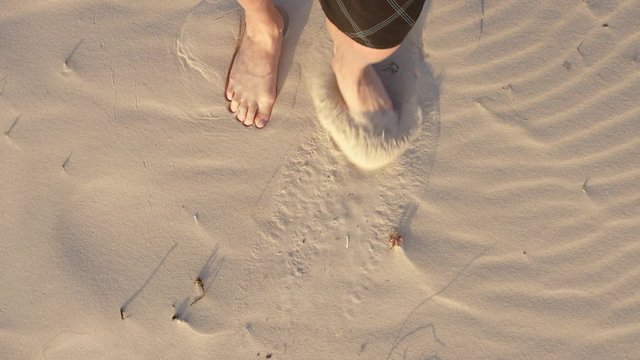 Barefoot man kicking garbage with leg in sand, top view. Sahara desrt