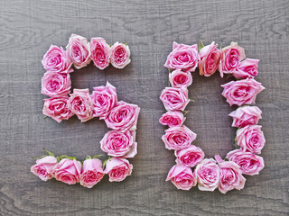 50, fifty - vintage number of pink roses on the background of dark wood - for congratulations, postcards, websites, design, printing