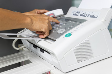hand man are using a fax machine in the office. Business concept 