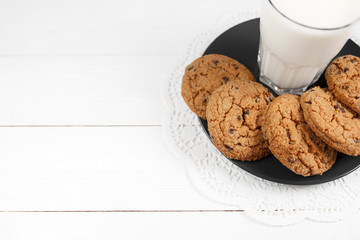 Tasty cookies and glass of milk on rustic white wooden background.