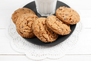Tasty cookies and glass of milk on rustic white wooden background.