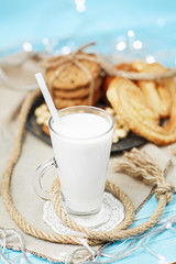 Glass of milk and tasty cookies on the vintage blue wooden background.