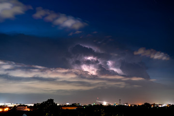 Thunder, lighting in the clouds at night sky above city