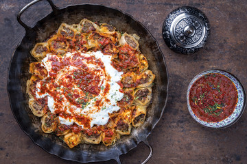 Traditional Turkey kolay yufka manti oven backed with lamb mincemeat as top view in a cast iron pan