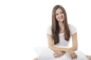 beautiful young girl smiling while sitting on bed with pillow