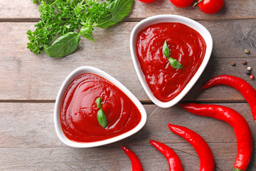 Composition with delicious tomato sauce and chili peppers on wooden table