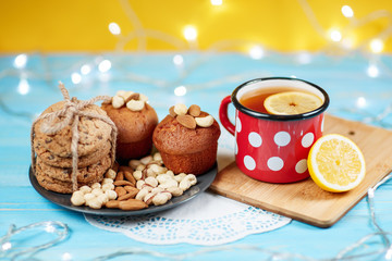 Composition of biscuits, cup of tea and lemon on the vintage background.