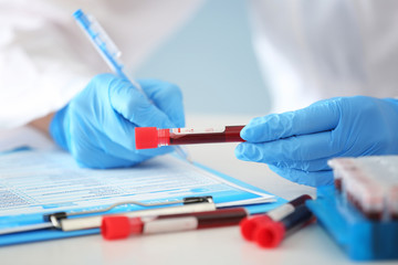 Woman working with blood sample in test tube at table