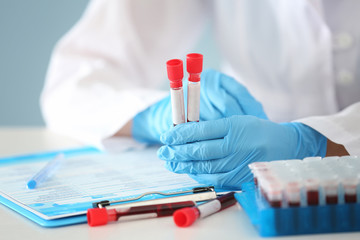 Woman working with blood samples in test tubes at table