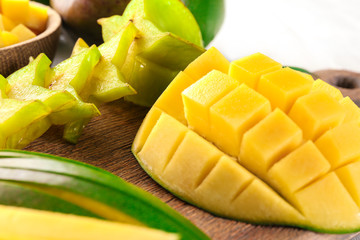 Cut fresh mango and starfruit on wooden board, closeup