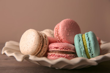 Plate with tasty macarons on table