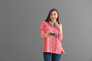 Young woman with gamepad on grey background © Pixel-Shot