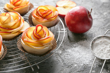 Rack with raw rose shaped apple pastry on table