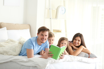 Happy family reading book together in bedroom