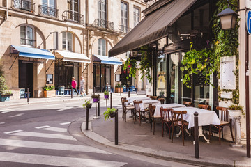 Naklejka premium Przytulna ulica z stołami kawiarni w Paryżu, Francja