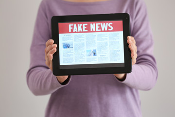 Woman holding tablet computer with news on screen