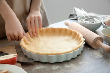 Woman preparing apple pie at table
