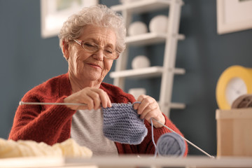 Senior woman knitting warm sock at home