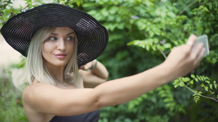 Young stylish beautiful woman in hat does selfie. Female using a smart phone