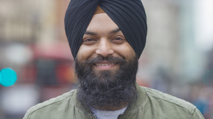 Portrait of smiling Indian male in a turban looking to camera on a street - 214742946