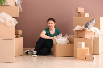 Young woman unpacking boxes indoors. Moving into new house