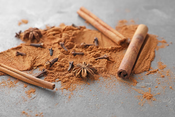 Aromatic cinnamon sticks, powder and spices on grey background