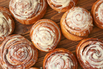 Tasty homemade cinnamon buns with glaze on wooden table, top view
