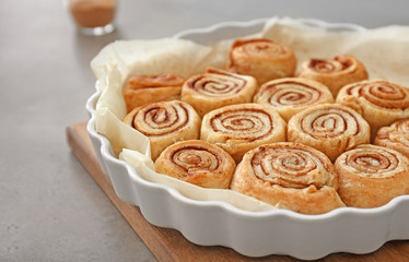 Baking dish with tasty cinnamon buns on table