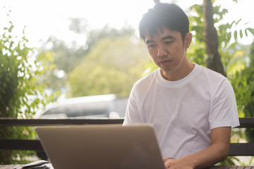 Asian man working on table outdoor.
